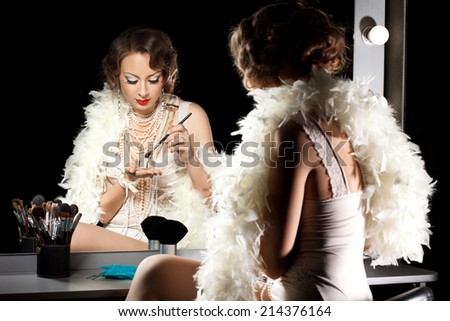 fashionable woman with make-up brush near the mirror