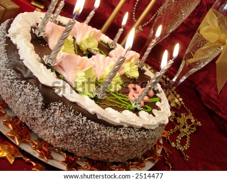 celebratory table (birthday cake and candles, two glasses with champagne, gift boxes) on red