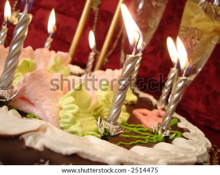 celebratory table (birthday cake and candles, two glasses with champagne) on red background