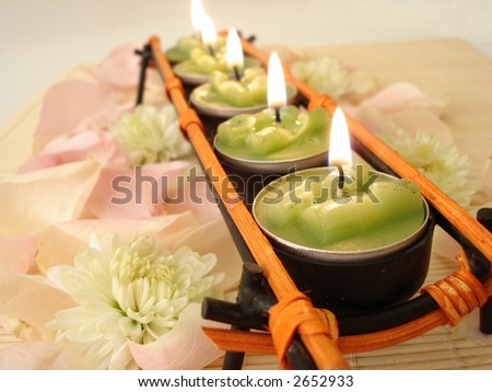 row of green candles over  straw matt with rose petals