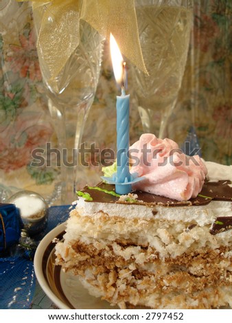 celebratory table (piece of birthday cake and blue candle, two glasses with champagne)