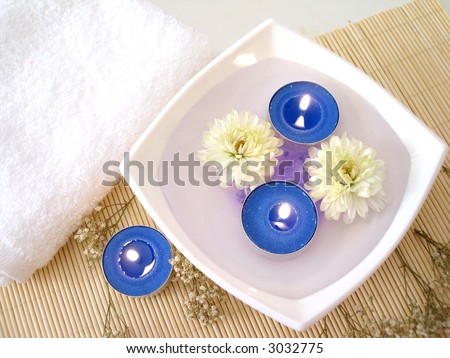 Spa essentials (white towel, blue candles and flowers in water)