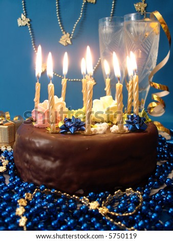 celebratory table (cake and candles, two glasses with champagne, gift boxes) on blue