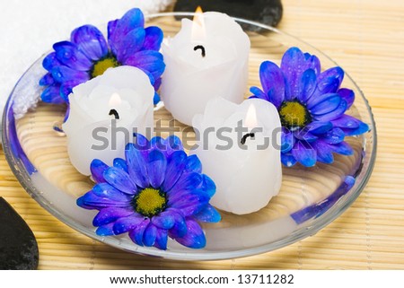 candles in water with blue flowers and towel