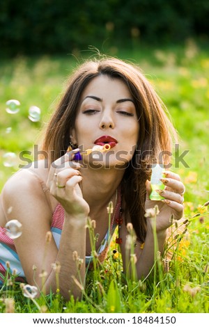 girl inflating soap-bubbles in field