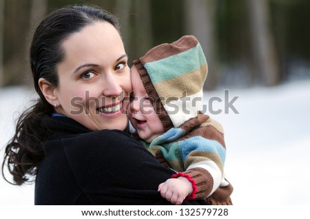 A happy and healthy middle-aged Mother with Child outdoors in a wintry scene. Focus is on the Mother.