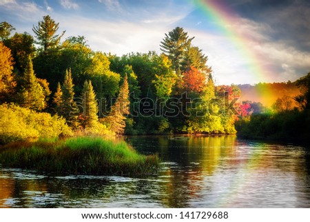 A Scenic Lake Or River During A Light Rain Displaying A Rainbow In The Mist On An Autumn Day Close To Sunrise Or Sunset.