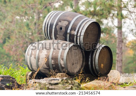 Three wine or whiskey barrels stacked outside on their sides.
