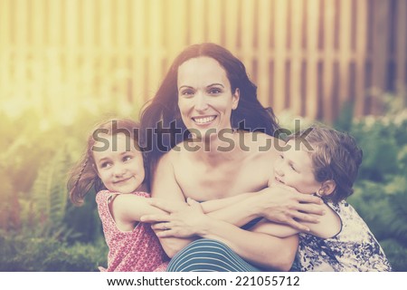 A close up family picture of two daughters on either side of their mother giving her a hug.  Filtered for a retro, vintage look.