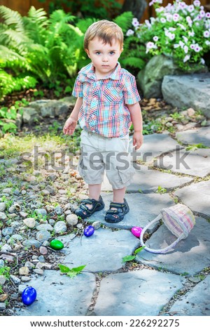 A young boy with a sad expression dropped his Easter basket on the ground outside during an Easter egg hunt.