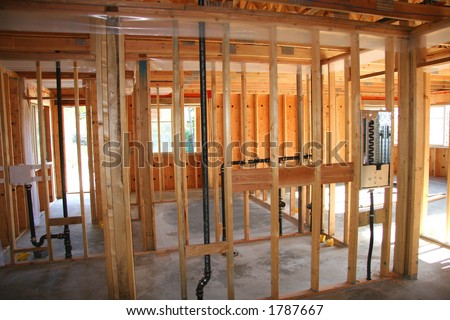 Framed walls of a house come together with basic plumbing.