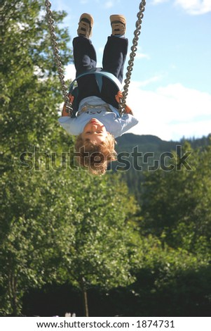A young boy gets so high on a swing that he appears upside down.