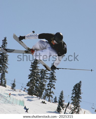 A skier styles a crossed ski rail grab in a terrain park at a ski hill mid winter.