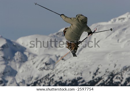 A skier styles a huge tip cross jump grabbing his ski in mid air with finesse.