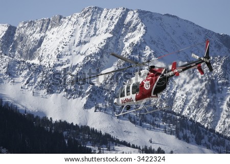 A medical helicopter flies injured skiers off a high mountain.