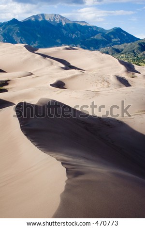Sand, sun and shadow form unique patterns of light and dark in the dunes of the Great Sand Dune National Park in southern Colorado - vertical orientation.