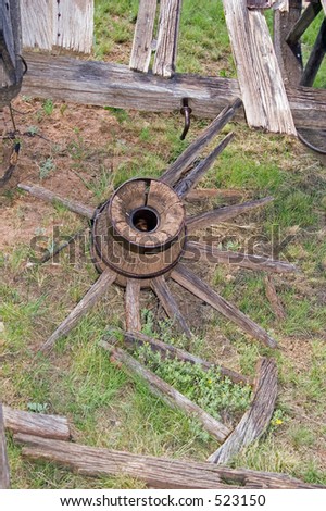 Broken parts of a wagon wheel and hub lie in the grass of an old parade ground.