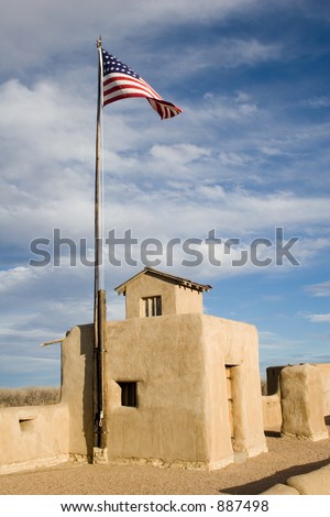 American flag over the adobe walls and ramparts of Old Bent\'s Fort historic site in Colorado - vertical orientation