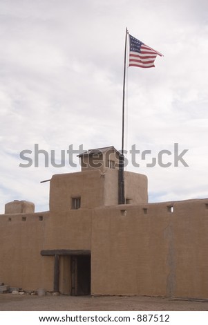 American flag over the adobe walls and ramparts of Old Bent\'s Fort historic site in Colorado - vertical orientation