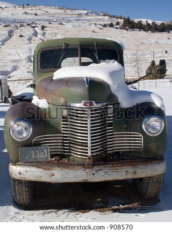 Old truck in the snow, with mountain behind