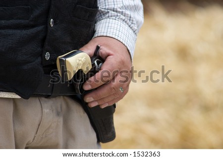 A steady hand rests on a crossdraw holster, worn low on the waist for a quick draw and fire.