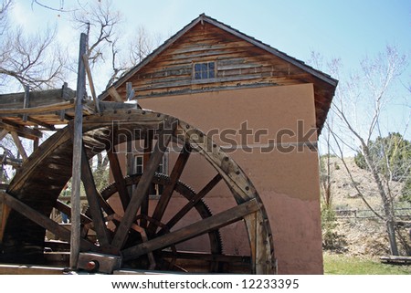 A old, but fully-working water-driven mill, with a rather large wooden waterwheel, located on the grounds of a museum in New Mexico.