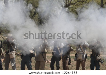 Gunpowder smoke obscures the faces of the uniformed participants in a Civil War reenactment in New Mexico.