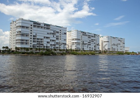 A set of three tall condominium buildings along the Space Coast in Florida, fronted by a calm ocean.