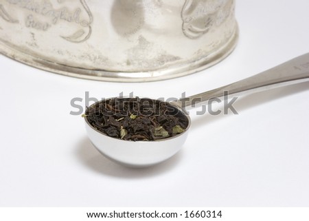 Loose Tea in Measuring Spoon in Front of Storage Tin, White Background