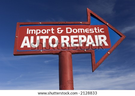 Arrow Shaped sign for auto repair shop against blue sky.