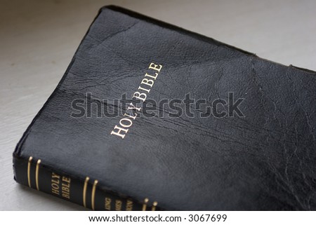 Partial view of Bible on white shelf in natural light, with shallow depth of field, focused on \