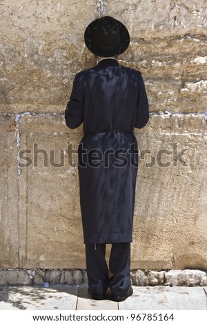 Single man, in Jewish garb, praying at the Wailing Wall or Western Wall in old town Jerusalem.