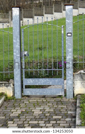 A small pedestrian gate that leads to a gress garden