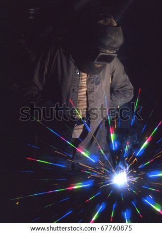 Man using electric arc welding equipment with cosmos filter on camera lens and flash fill.