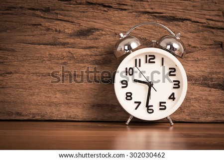 white alarm clock on wooden old background, red vintage clock on wooden table