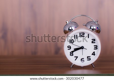 white alarm clock on wooden old background, red vintage clock on wooden table