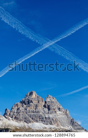 Vapor trails after flying machines above the mountain top