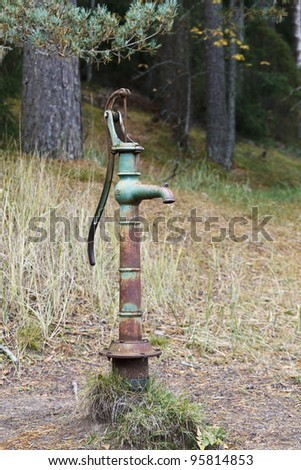 Old hand operated water pump from a spring in the forest