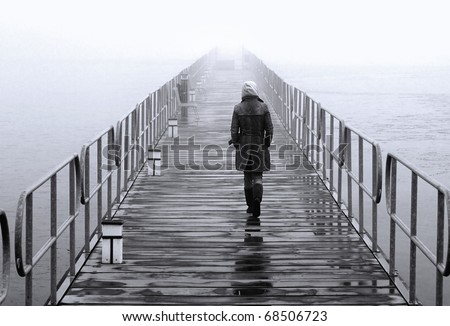 A lonely lady crossing the floating pedestrians\' bridge that leads to the islet of Aghios Achilleios in Mikri Prespa lake