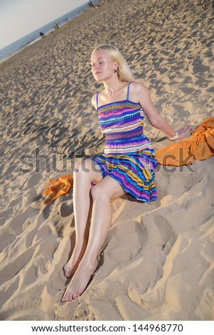 Woman in lined dress take sunbath on beach