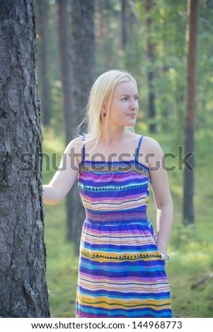 Woman in lined dress next to tree stem