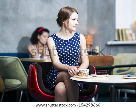 Zoomed woman in spotted dress sit in cafe