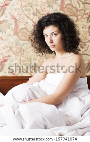 Woman under soft cover seems serious of something