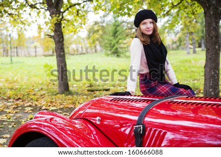 Young woman in skirt on red car cowling