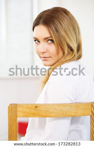 Charming woman on chair with over the shoulder look
