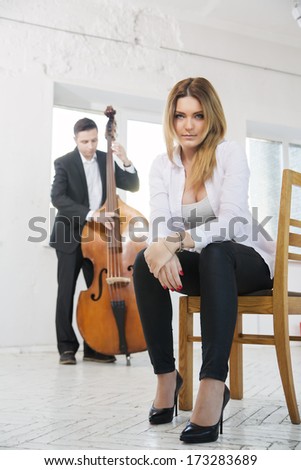 Young woman on stool and man plays melody