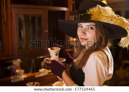 Zoomed woman at fashioned dress with porcelain cup