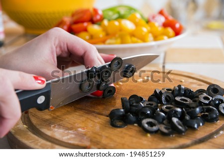 Woman soft fingers cut black olives to slices