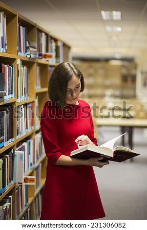 Young woman in library near shelves with book
