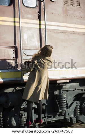 Woman in coat climbs the ladder at wagon